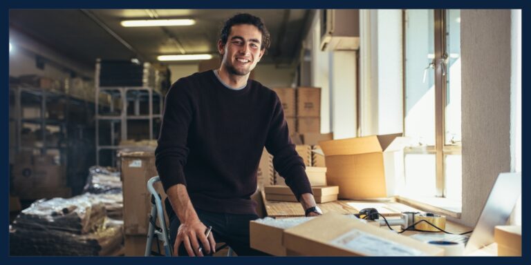 Man working at his small business smiles at the camera.