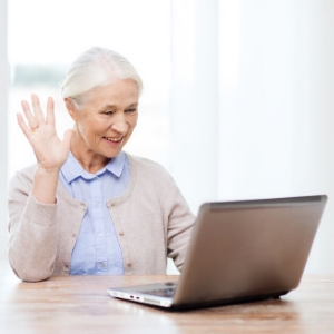 Woman on video call waving to laptop