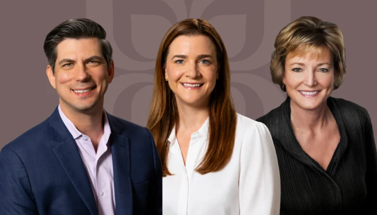 Three professionals smiling together, representing collaboration and success in mergers and acquisitions at Mission Wealth.