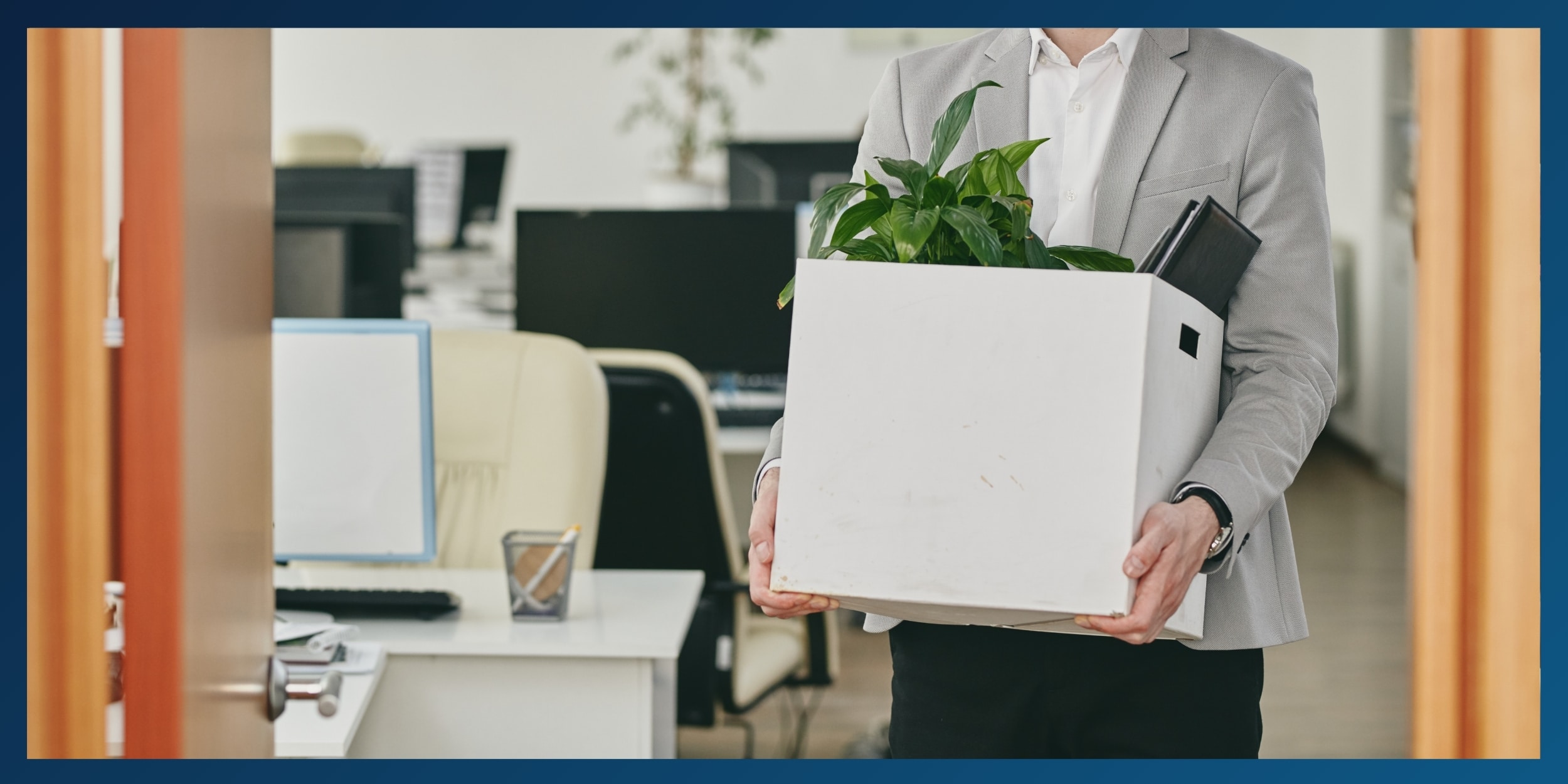 A man carrying a box of personal items from his desk while leaving the office.