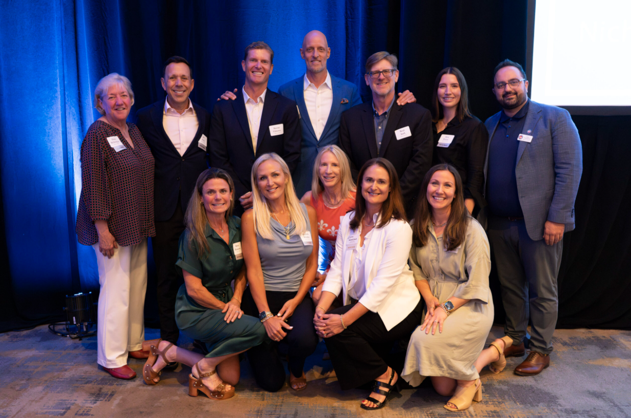 Dannell, wearing a white blazer, poses with Mission Wealth colleagues at a team event.