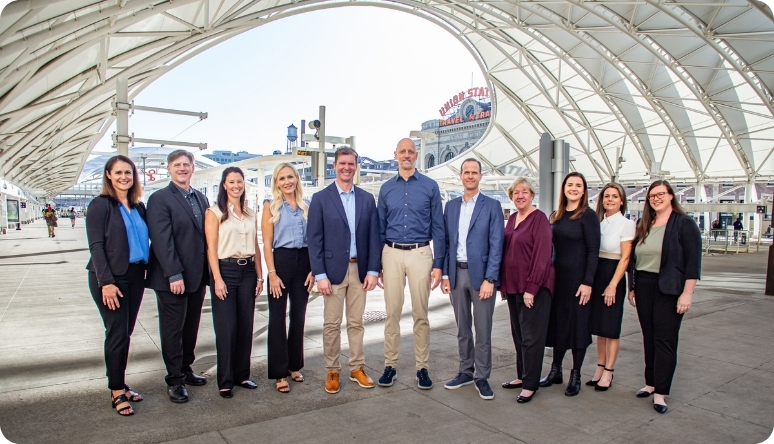 Diane Williamson Mission Wealth team poses together outdoors under a modern structure, showcasing their collaborative spirit.