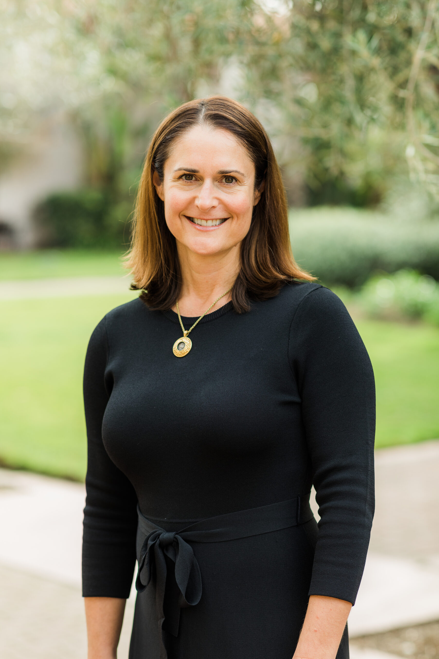 Professional outdoor portrait of Dannell wearing a black dress and gold necklace.