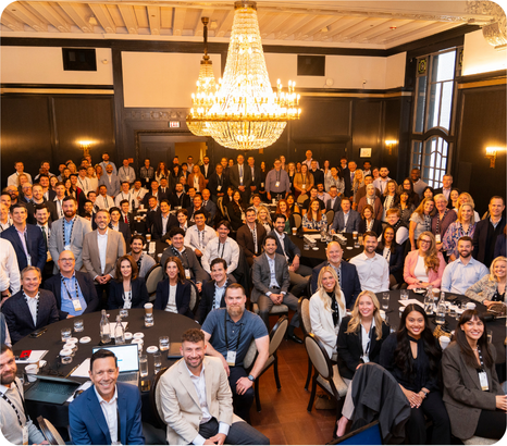 Large group of Mission Wealth team members gathered in an event space beneath a chandelier