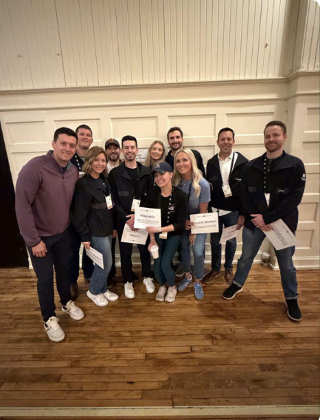 Mission Wealth team members posing together indoors, with several holding certificates
