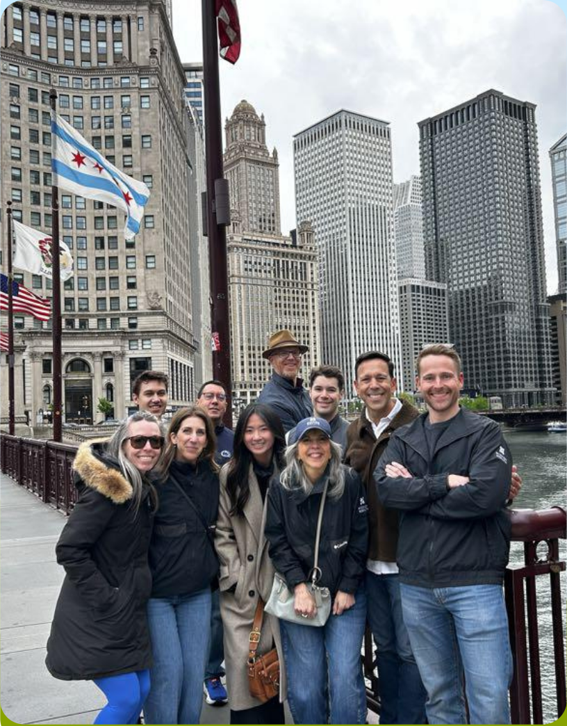 Mission Wealth team members posing outdoors along the Chicago River with downtown buildings behind them