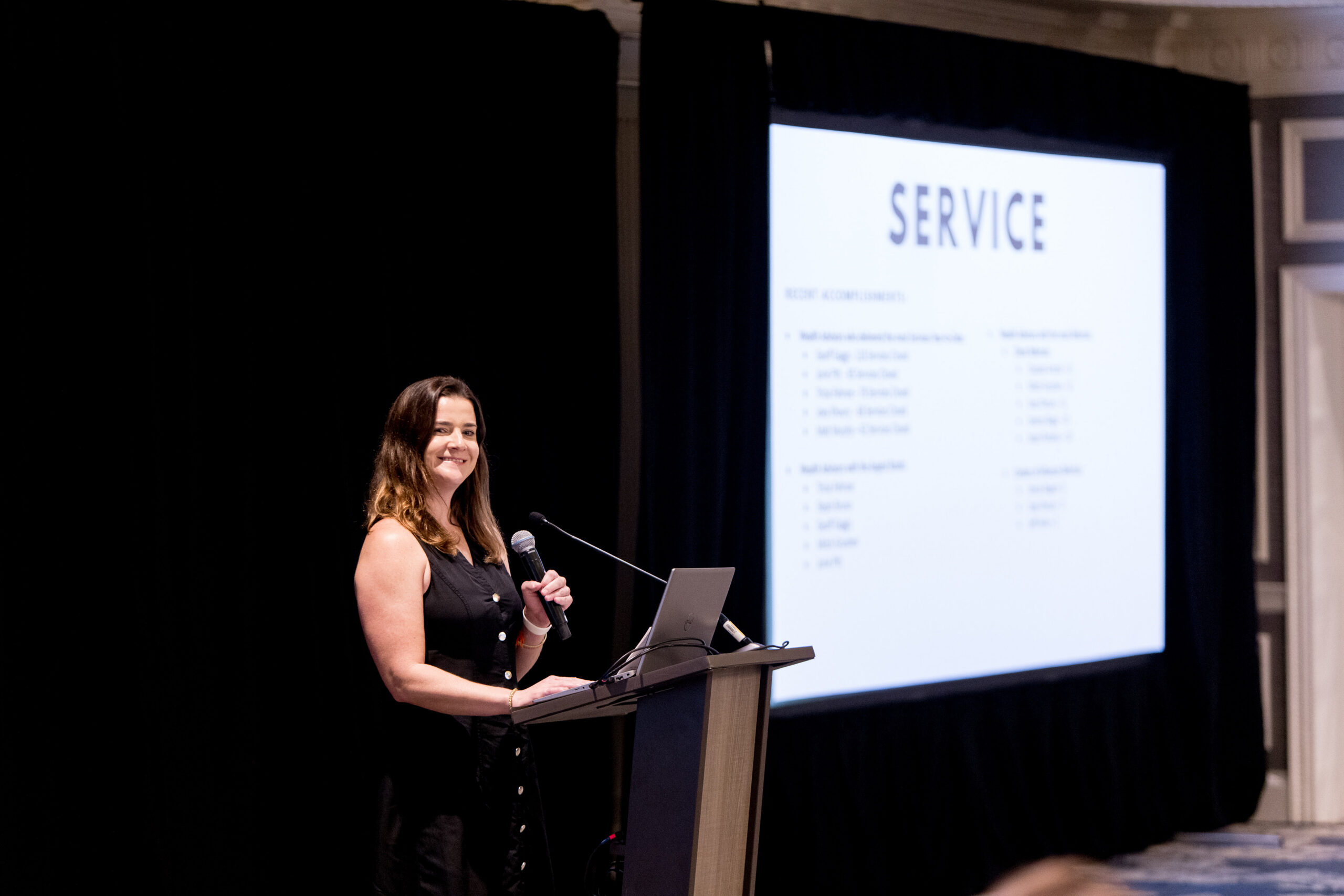 Sara Clark presents from a podium during a Mission Wealth team event.