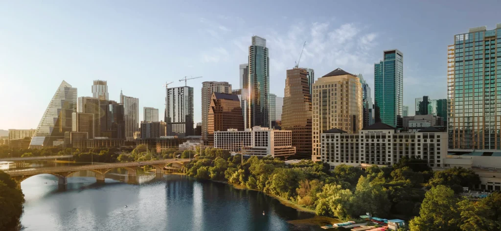 Austin's skyline at sunset, showcasing modern skyscrapers and the serene waters of the Colorado River.