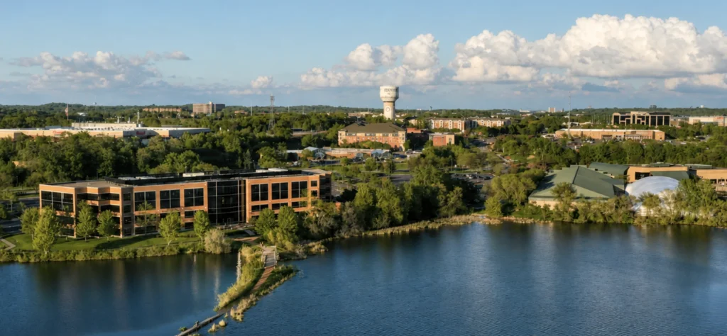 Aerial view of Eden Prairie showcasing commercial buildings and lush greenery alongside a serene lake.