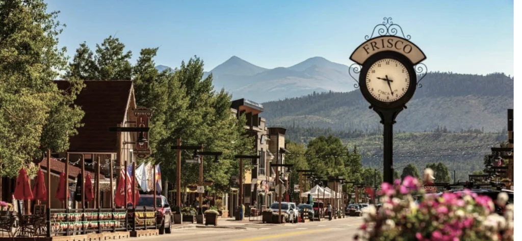 Charming Frisco street scene featuring a vintage clock, shops, and mountains in the background.