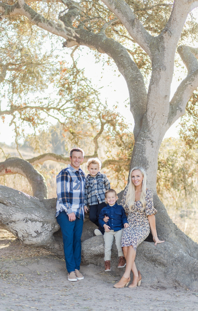 Family portrait of Michelle Winkles with her two children and husband, set against a scenic tree backdrop.