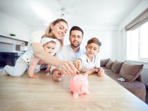 family putting money into a piggy jar
