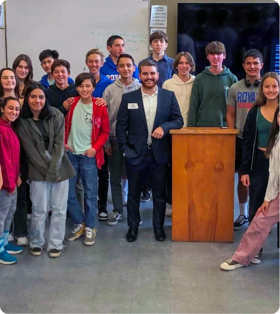 Students and a mentor gather in a classroom, illustrating the Mission Wealth community impact through engagement and support.