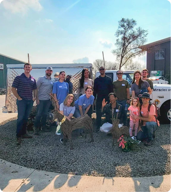 Mission Wealth community impact volunteers gather for a group photo during a charitable event, smiling and engaging.
