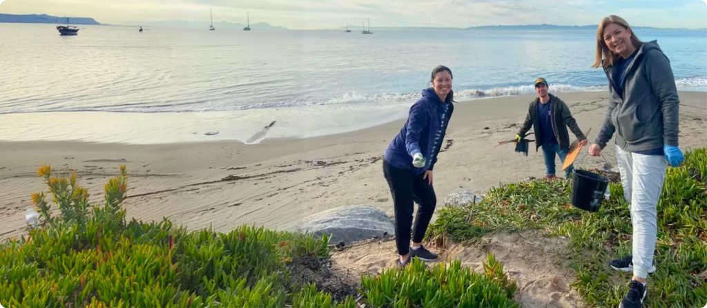 Volunteers from the Mission Wealth community impact clean up a beach, promoting environmental stewardship and community engagement.