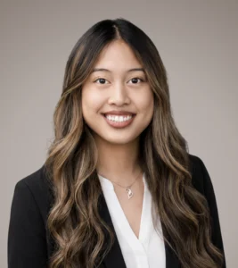 Professional headshot of Martina Mendoza with long wavy hair, wearing a black blazer over a white blouse, smiling warmly.