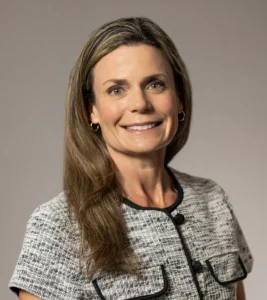 Renee Hennessee, a professional at Mission Wealth, smiles confidently in a stylish, tailored outfit against a neutral background.