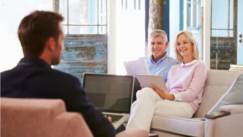 A financial advisor discusses retirement strategies with a smiling couple in a bright, inviting setting.