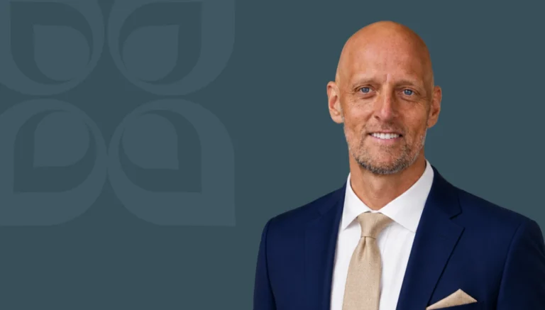 Professional man in a suit smiles confidently against a dark background, illustrating insights on avoiding psychological traps.