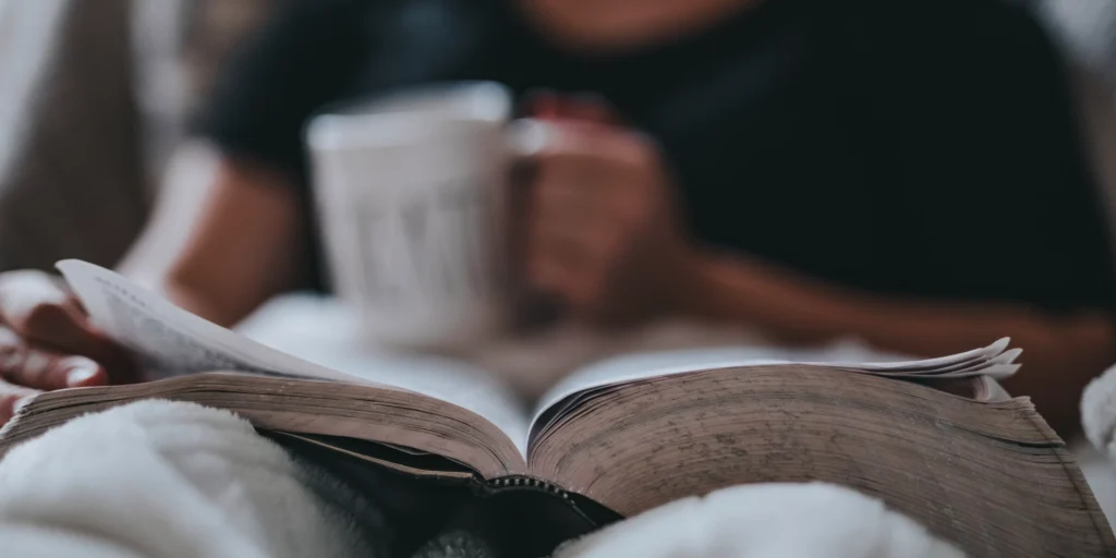 A cozy scene featuring a person reading a book with a warm drink, emphasizing the blend of knowledge and emotion in investing.