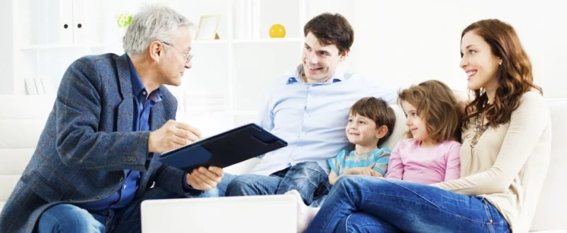 A financial advisor discusses investment strategies with a family in a bright, modern living room.