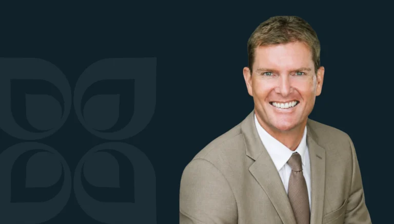 Rick D. Gonzalez smiles confidently in a suit against a dark background, representing success in Mergers & Acquisitions.