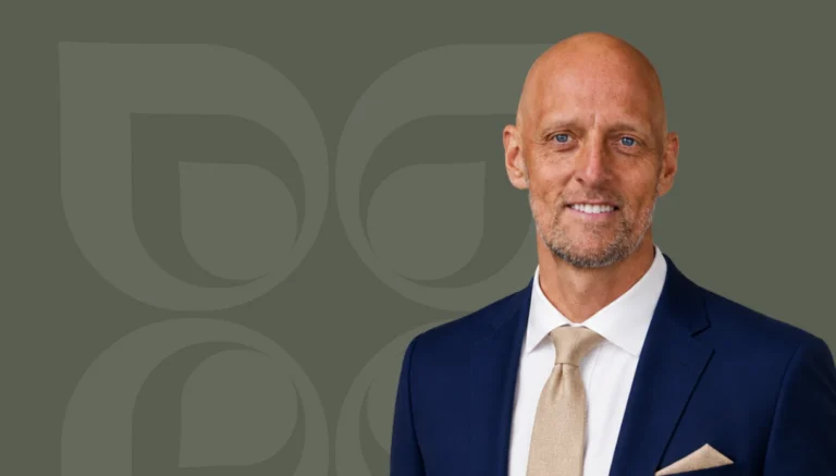Professional man in a suit smiling, representing expertise in investment strategies for Mission Wealth Management.