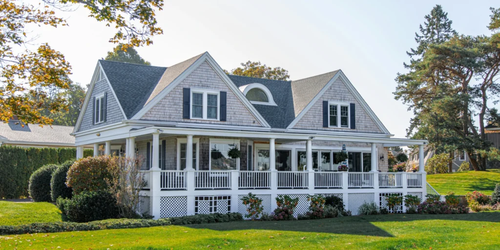 Charming white house with a porch surrounded by greenery, illustrating the importance of property insurance for homeowners.