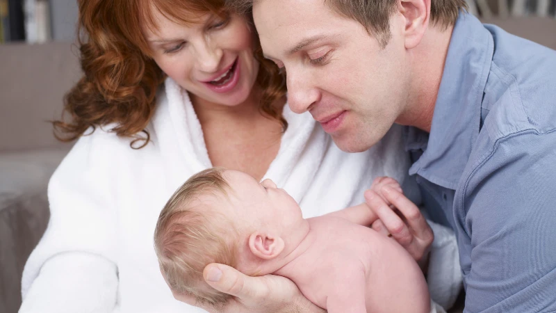 New parents joyfully gaze at their newborn baby, emphasizing love and connection in the journey of parenthood.