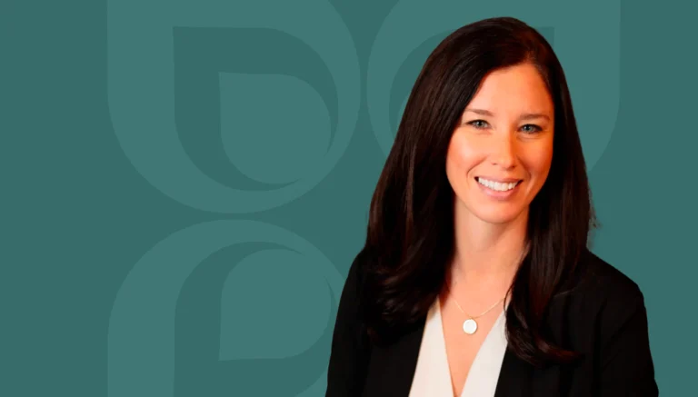 Professional woman with long dark hair smiles against a teal background, representing a corporate or business setting.
