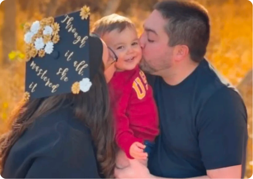 A joyful family moment with a mother and father kissing their smiling toddler, celebrating a graduation milestone.