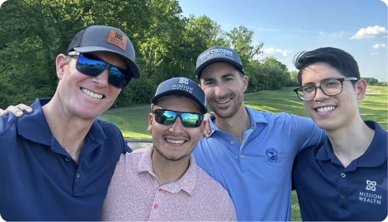 Four men smiling together outdoors on a golf course, wearing casual attire and caps, promoting camaraderie and teamwork.