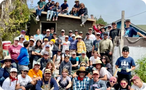 A large group of volunteers poses together outside a building, showcasing community spirit and teamwork during a service project.