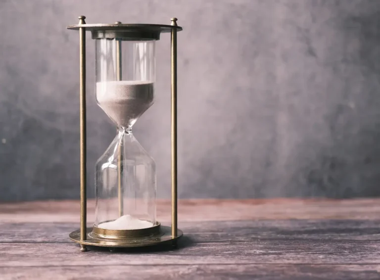 An antique hourglass with flowing sand, symbolizing the passage of time against a textured background.