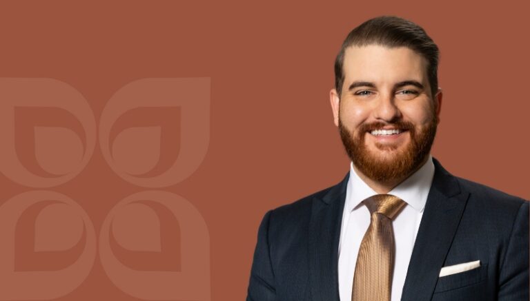 Smiling professional in a suit against a warm background, representing Mission Wealth's financial confidence services.