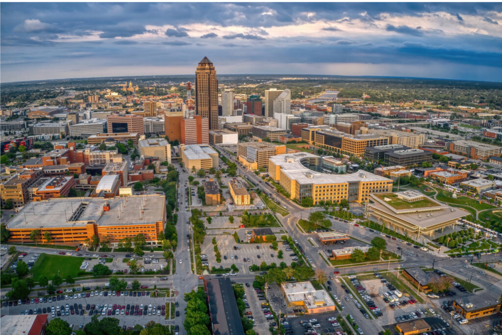 Aerial view of downtown Des Moines showcasing urban buildings, parks, and streets under a dramatic sky.