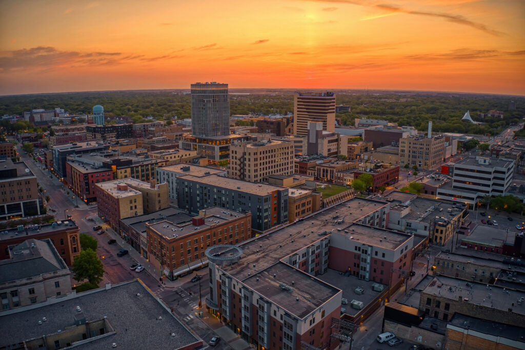 Aerial view of Fargo at sunset, showcasing urban buildings and streets against a vibrant sky.